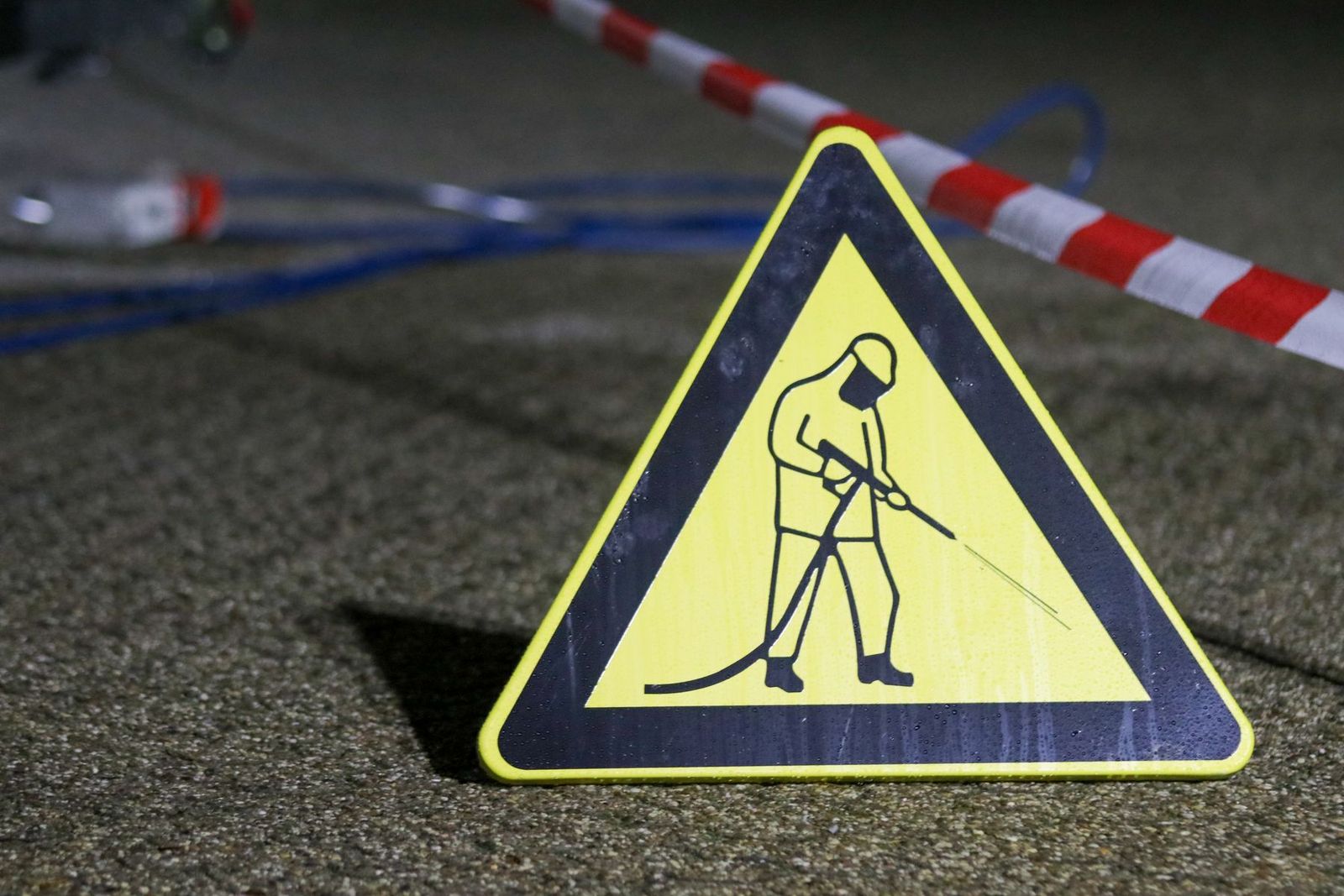 Gelbes Warnschild für Hochdruckreinigung mit Absperrung